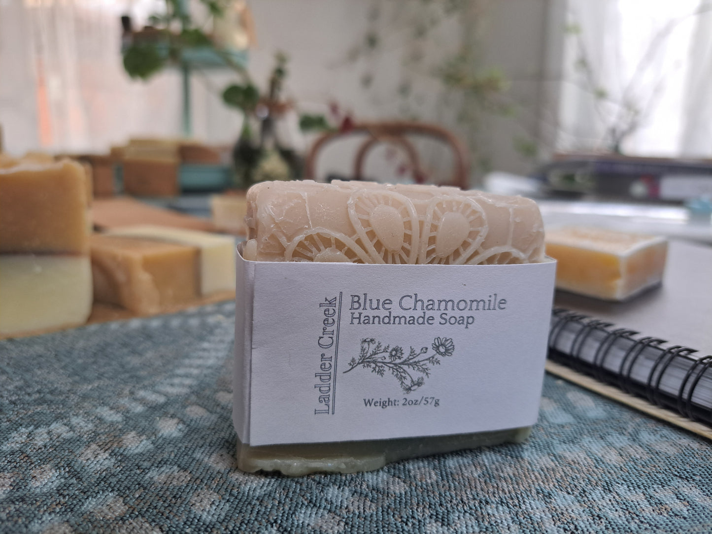 Bar of Blue Chamomile handmade soap with a decorative label on a textured surface.