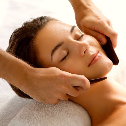 Person receiving a face massage with a neutral background
