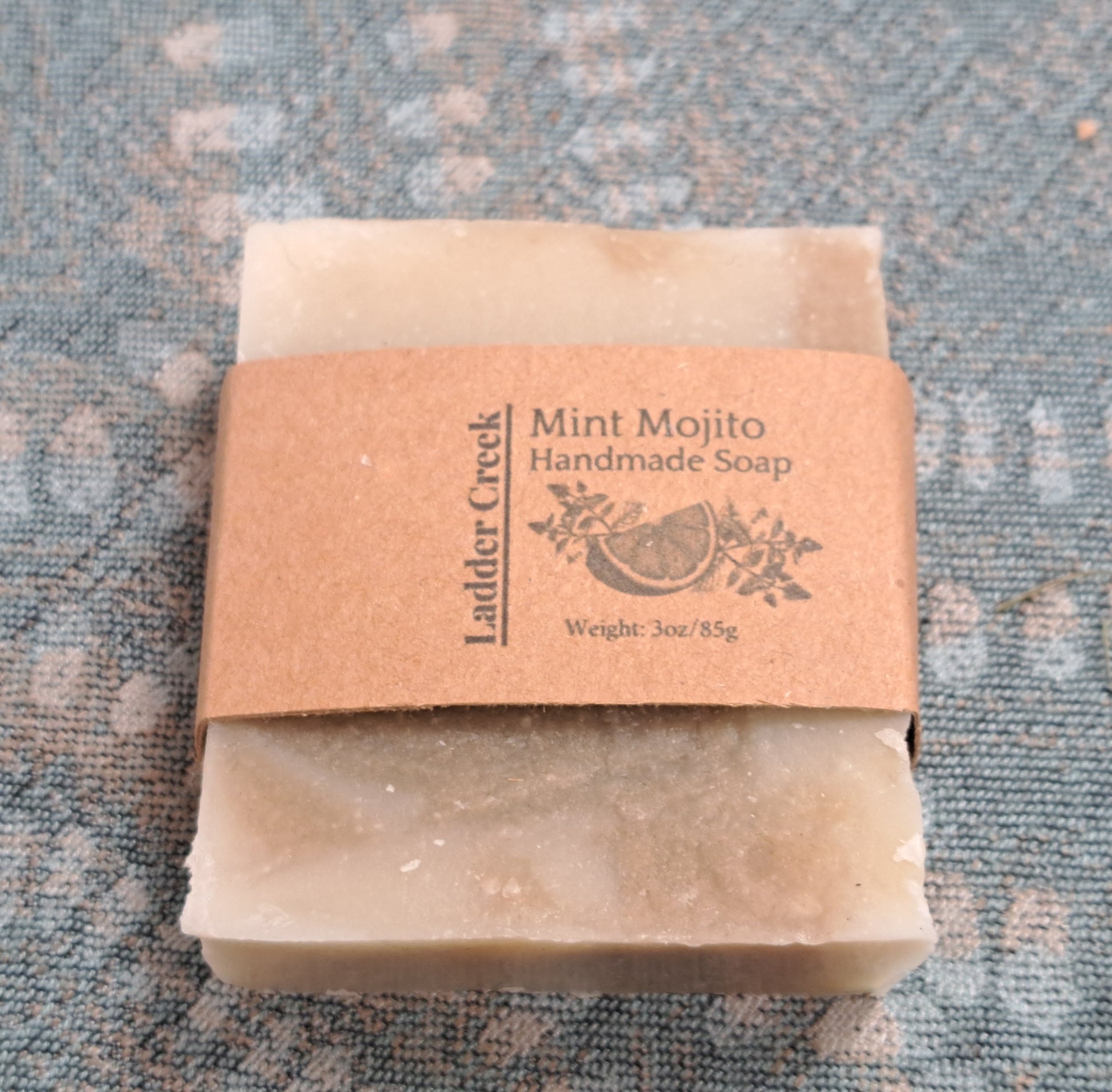 Handmade soap bar with a brown label on a textured blue fabric background