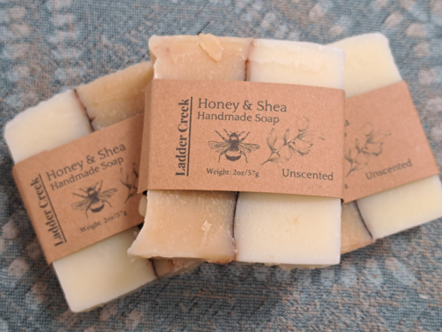 Handmade soap bars with Ladder Creek branding on a textured surface