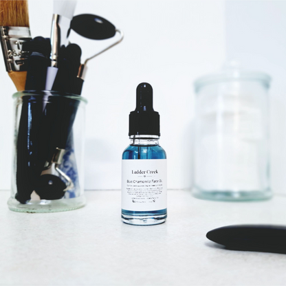 Bottle of Ladder Creek facial oil with makeup tools on a white surface