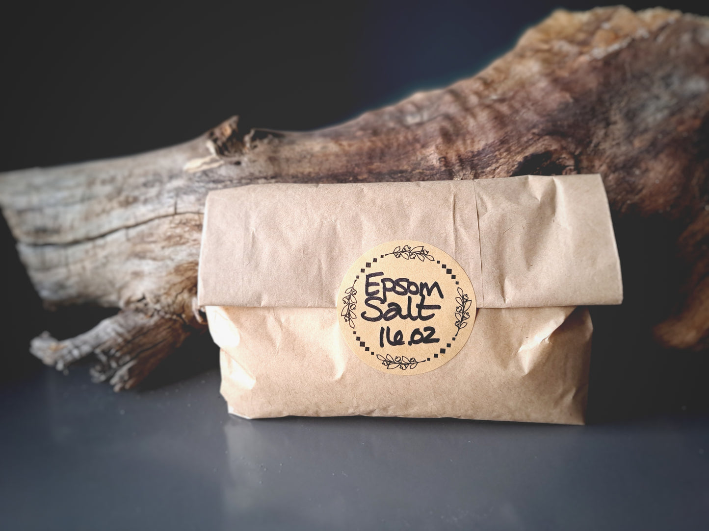 Brown paper package labeled 'Epsom Salt 14 oz' with a wooden background.