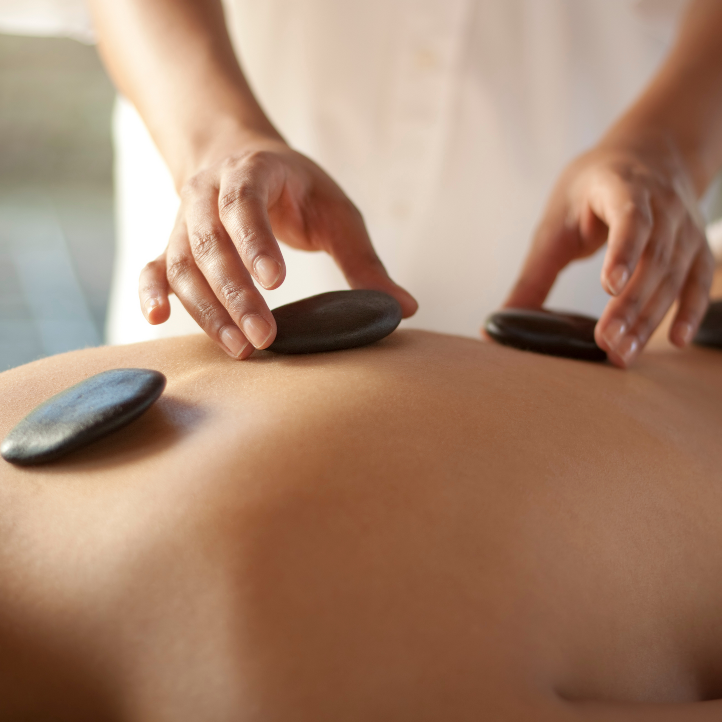 Stones being used for a massage on a person's back
