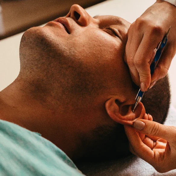 Person getting an ear seed placed with a pencil shaped  instrument