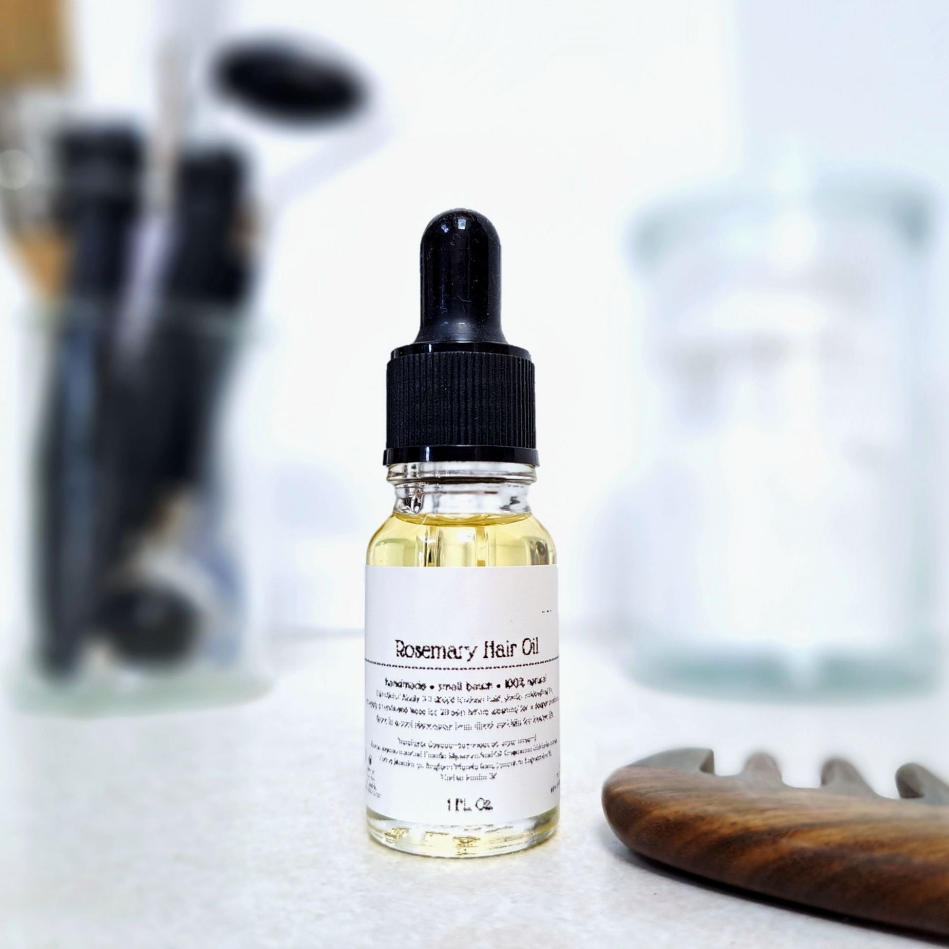 Bottle of Rosemary Hair Oil with a dropper on a blurred background